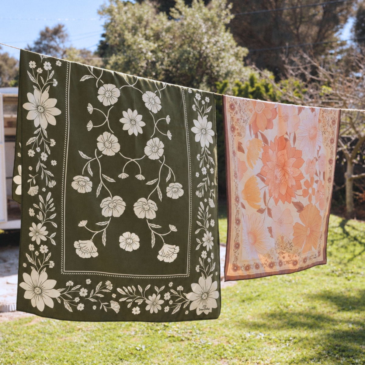 Eden sand free beach towel in Large, olive green floral bandana print, on a washing line
