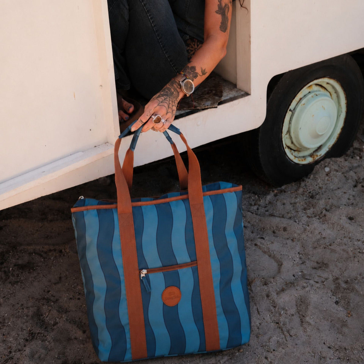 Jagger Tidal beach tote bag, two-tone blue wavy stripe, on the sand by a caravan