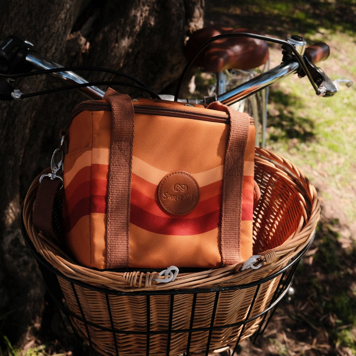Stevie mini insulated cooler bag, orange retro 70s wave print, in a bike basket