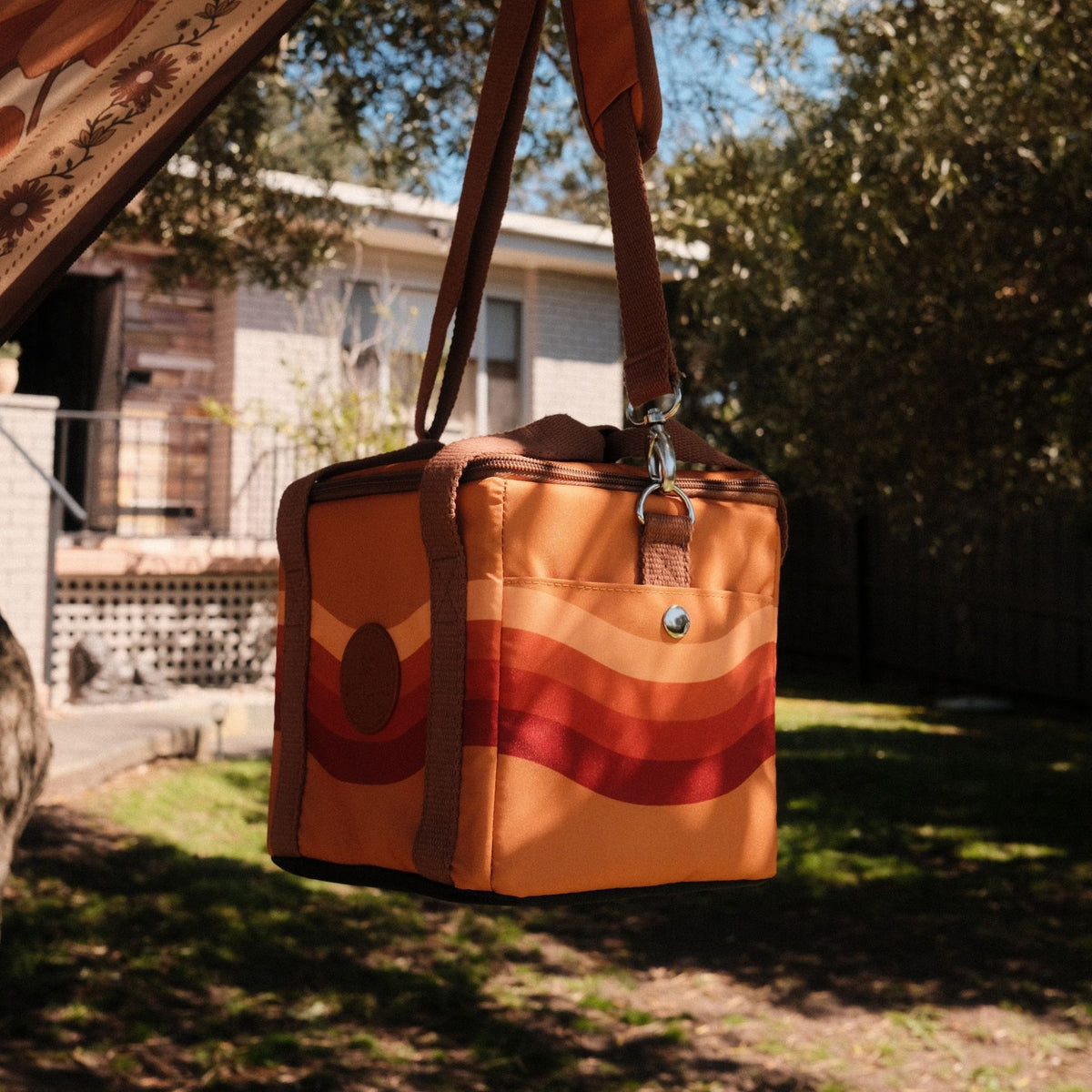 Stevie mini insulated cooler bag, orange retro 70s wave print, hanging by its shoulder strap