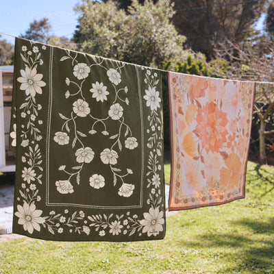Eden sand free beach towel in Large, olive green floral bandana print, on a washing line