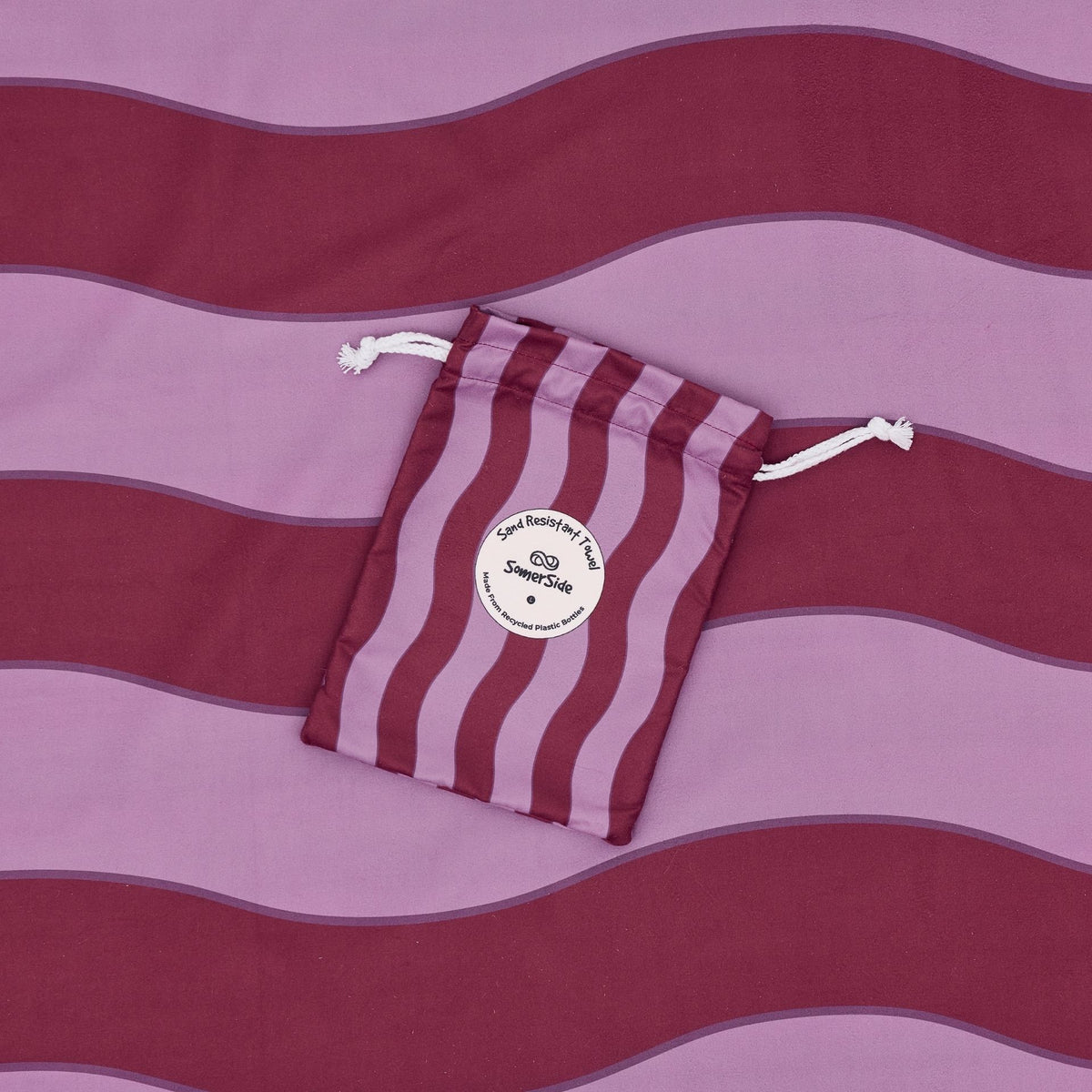 Jagger Shiraz sand free beach towel in Large, burgundy and mauve wavy stripe, with its carry pouch