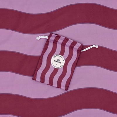 Jagger Shiraz sand free beach towel in Large, burgundy and mauve wavy stripe, with its carry pouch