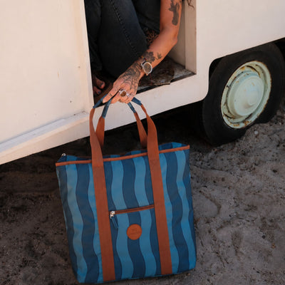 Jagger Tidal beach tote bag, two-tone blue wavy stripe, on the sand by a caravan