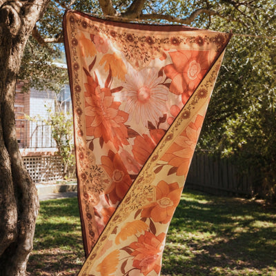 Summer Muse sand free beach towel, peach retro 70s floral print, on a washing line in the garden
