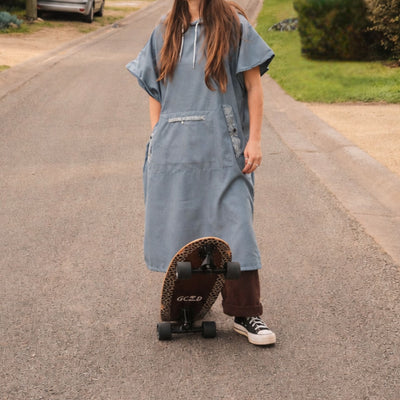 Venice adult hooded towel poncho, dusty blue paisley bandana print, with a skateboard