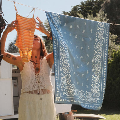 Venice sand free beach towel, dusty blue paisley bandana print, on a washing line